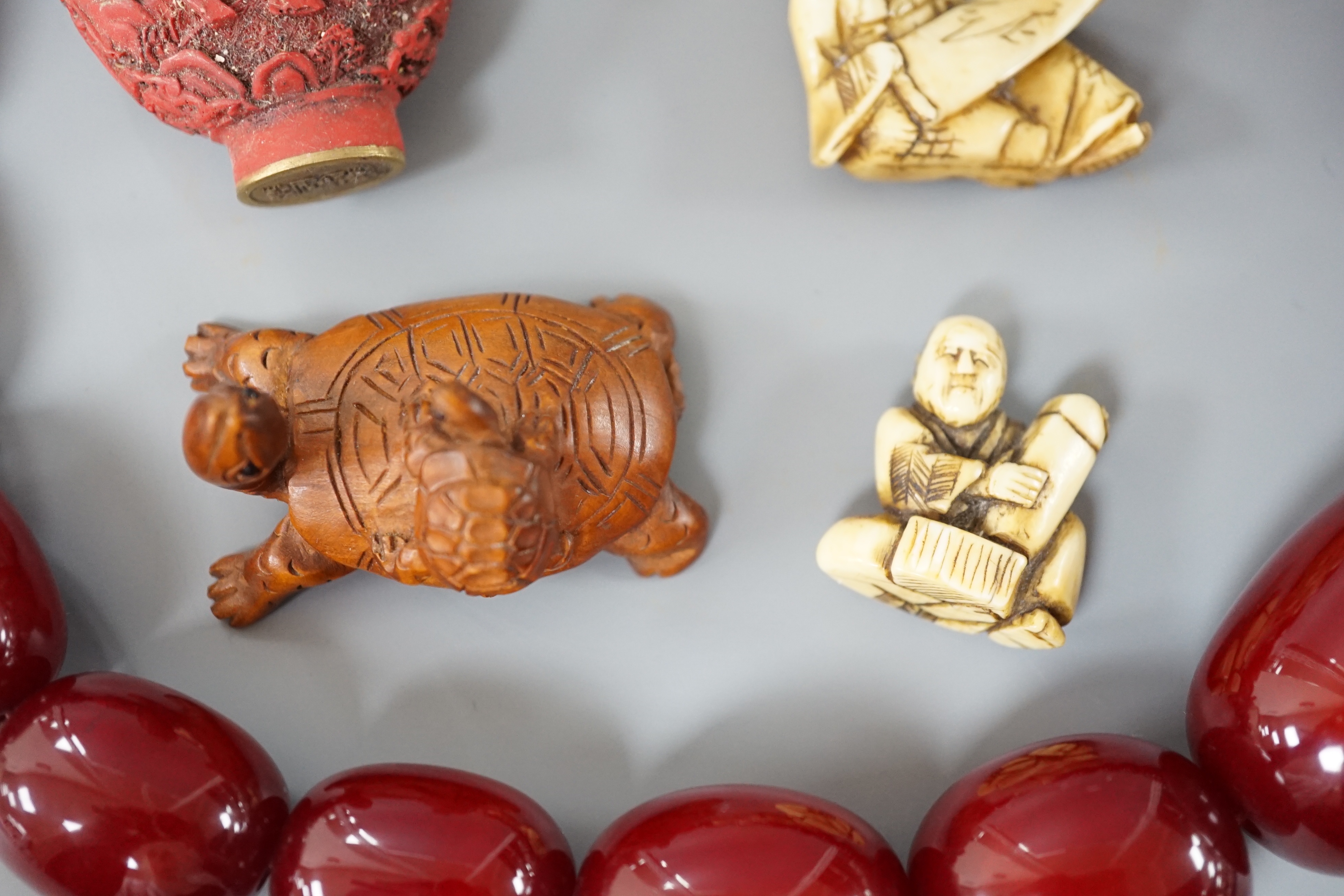 Assorted Chinese and Japanese Ivory and wood carvings, a scent bottle and a simulated cherry amber bead necklace, Necklace 52 cms long.